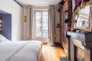 Chambre avec cheminée décorative, armoire et parquet ancien dans un appartement à vendre Paris 18 Montmartre