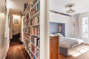 Couloir avec bibliothèque et accès à la chambre parentale parquetée dans un appartement à vendre Paris 18 Montmartre