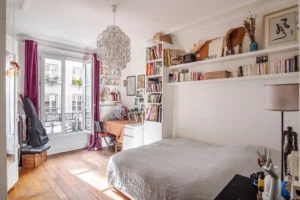 Chambre lumineuse avec bibliothèque, bureau et balcon dans un appartement à vendre Paris 18 Montmartre