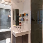 Salle de bain moderne avec baignoire, douche et double vasque dans un appartement à vendre Paris 18 Montmartre