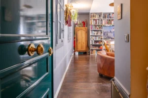 Entrée d’appartement avec porte ancienne et parquet donnant sur un salon bibliothèque à vendre Paris 18 Montmartre