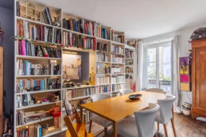 Salle à manger conviviale avec grande bibliothèque et parquet ancien dans un appartement à vendre Paris 18 Montmartre