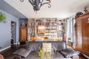 Salon avec canapé en cuir et grande bibliothèque intégrée dans un appartement à vendre Paris 18 Montmartre