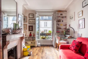Pièce lumineuse avec cheminée ancienne, bureau et balcon fleuri dans un appartement à vendre Paris 18 Montmartre