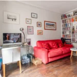 Bureau avec bibliothèque murale et canapé rouge dans un appartement à vendre Paris 18 Montmartre