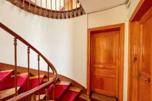 Palier d’étage avec porte d’entrée en bois massif et rampe d’escalier élégante.