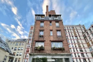 Façade en brique de l’immeuble ancien typique du Canal Saint-Martin, avec ciel bleu et lumière de fin de journée.