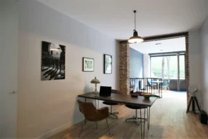 Bureau ouvert dans un local commercial à Paris 20ᵉ – luminosité naturelle et mur en briques