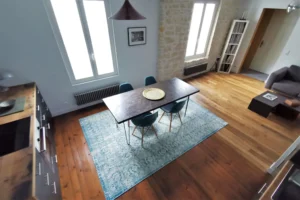 Prise de vue en hauteur d’une cuisine ouverte contemporaine et design avec une table en béton cirée gris.