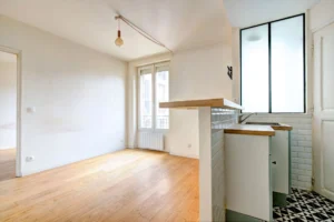 Séjour lumineux avec parquet, cuisine ouverte à aménager et verrière intérieure.