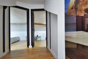 Paliet avec parquet en chêne au sol et mur blanc qui distribue deux chambres avec salle de bains