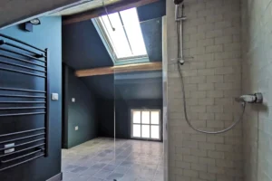 Salle d’eau moderne avec poutres et douche sous combles