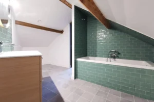 Salle de bain sous pente avec double vasque et carrelage vert