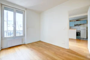Chambre claire avec fenêtre double vitrage et vue dégagée sur les toits parisiens.