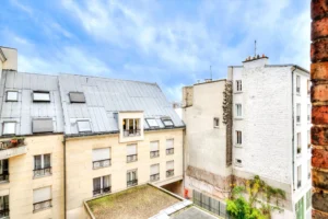 Vue dégagée sur cour intérieure avec immeubles parisiens et ciel bleu.