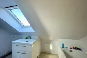 Salle de bains à l’étage avec baignoire et vasque sous vélux, maison à Pont-l’Évêque.