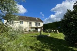 Façade de la maison avec jardin ensoleillé à vendre à Pont-l’Évêque, environnement calme et verdoyant.