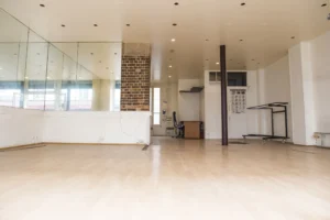Espace bureau d’un local commercial à Paris 19ᵉ avec mur en brique, sol en parquet et nombreux points lumineux.