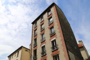 Façade de l'immeuble ancien en briques rouges et blanches à Ménilmontant, Paris 20ᵉ, où se situe le local commercial à vendre.