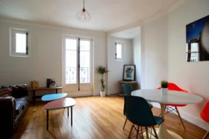 Salon lumineux avec parquet en bois massif, mobilier design et fenêtres à double vitrage – appartement à vendre à Belleville, Paris 19ᵉ.