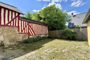Façade à colombages traditionnelle dans une cour privative d’un appartement à vendre à Pont-l’Évêque, typique de l’architecture du Pays d’Auge.