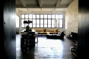 Vaste loft lumineux à Bagnolet, avec verrière atelier, murs en briques blanchis, sol en béton ciré et mobilier contemporain, dans un esprit industriel chic.