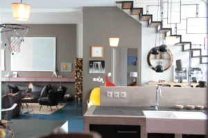 Vue intérieure d’un loft design à Paris 10, mêlant cuisine en béton brut, salon cosy et escalier graphique, dans le quartier Faubourg Saint-Denis proche de la Gare de l’Est.
