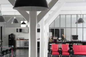 Loft industriel lumineux à Paris 10, avec poutres apparentes, cuisine ouverte et mobilier design, situé entre la rue du Faubourg Saint-Denis et Gare de l’Est.