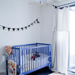 Chambre d’enfant lumineuse avec lit à barreaux bleu, jouets colorés et décoration murale, dans un loft familial à vendre à Paris 10ᵉ, quartier Faubourg Saint-Denis.