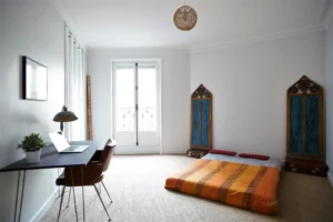 Grande chambre avec sol naturel, lit au sol et décoration exotique inspirée de l’artisanat – appartement à vendre à Paris 19ᵉ, Belleville.