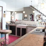 Cuisine en béton brut dans un loft parisien, avec plan de travail carrelé, évier d’atelier, suspensions modernes et ambiance industrielle au cœur du 10e arrondissement.