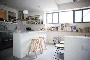Cuisine lumineuse avec plan de travail en marbre, étagères ouvertes et décoration murale, dans un appartement à vendre à Paris 10ᵉ, rue Martel.