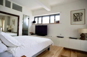 Chambre parentale lumineuse avec parquet clair, miroir sur mesure, lit double et rangements, dans un appartement à vendre Paris 10ᵉ rue Martel.
