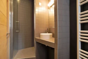Salle d’eau moderne avec douche à l’italienne, vasque design et carrelage gris – appartement à vendre à Belleville, Paris 19ᵉ