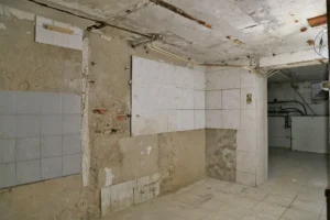 Pièce secondaire du sous-sol avec carrelage et murs à rénover, idéale pour création de sanitaires ou rangements.