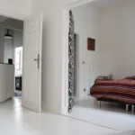 Suite parentale avec chambre et salle de bains attenante, sol blanc, motifs graphiques et ambiance contemporaine dans un loft à Paris 10ᵉ.