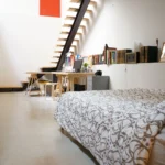 Espace chambre avec bibliothèque, bureau d’artiste et escalier graphique dans un loft à Paris 10ᵉ