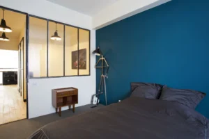 Vue depuis la chambre sur la verrière industrielle donnant sur la pièce de vie, déco sobre et élégante.