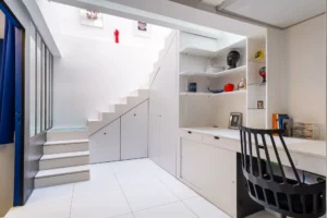 Coin bureau aménagé sous escalier, avec rangements intégrés et lumière zénithale, dans un espace optimisé.