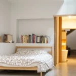 Chambre avec tête de lit bibliothèque et accès à une salle de bains dans un loft à Paris 10ᵉ