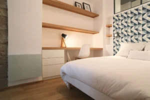 Vue en perspective du couloir d’entrée, avec éclairages intégrés, plafond sombre et parquet bois clair dans un loft parisien.