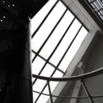 Escalier en métal sous verrière de toit dans un loft parisien, ambiance industrielle avec lumière zénithale, situé dans le 10ᵉ arrondissement de Paris.