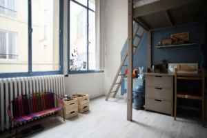 Chambre d’enfant avec lit mezzanine, coin bureau et grande fenêtre sur cour intérieure dans un loft à Paris 10ᵉ.