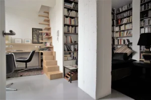 Espace bureau avec bibliothèque murale et escalier design en bois, dans un appartement à vendre Paris 10ᵉ rue Martel.