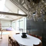 Salle à manger design dans un loft à Bagnolet, avec table en marbre, suspension contemporaine à globes et vue dégagée sur le séjour lumineux.
