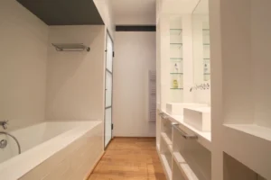 Salle de bains contemporaine, avec baignoire intégrée, double vasque, grands miroirs et rangements ouverts à Paris 10.