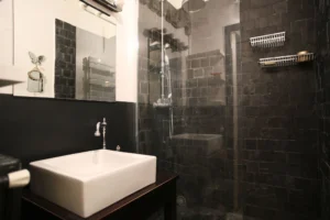 Salle de douche moderne avec carrelage noir, grande vasque et robinetterie chrome dans un loft situé rue du Faubourg Saint-Denis à Paris 10ᵉ.