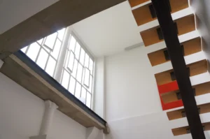 Vue d’ensemble d’un espace nuit avec bureau, bibliothèque et escalier dans un loft à Paris 10ᵉ