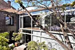 Façade panoramique vitrée d’un loft à Bagnolet, intégrée à un écrin de verdure, offrant une transparence totale entre intérieur et extérieur.