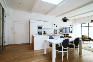 Cuisine ouverte moderne et salle à manger dans un loft lumineux à Paris 10, avec mobilier design, verrière atelier et parquet en chêne clair.